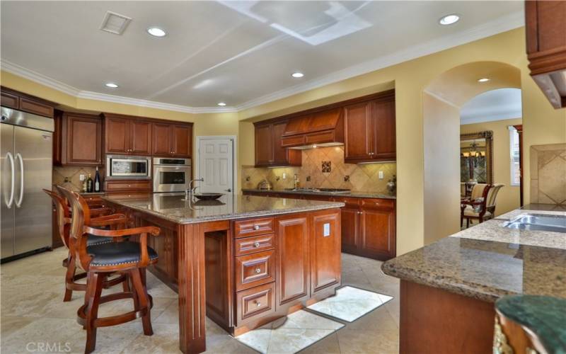 Gourmet kitchen featured with recess lights, travetine floors, large island, cherry cabinets, walk-in pantry, stainless steel appliances.