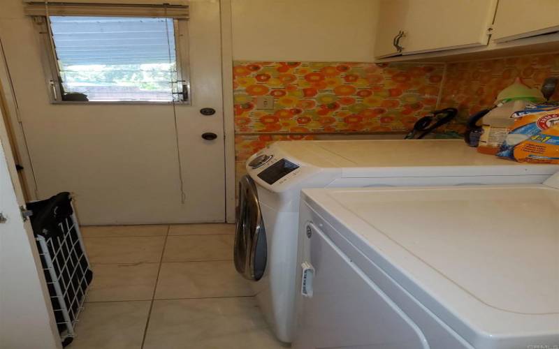 Large laundry room with, basin sink, large cabinets, 1/2 bath and exit door to patio.