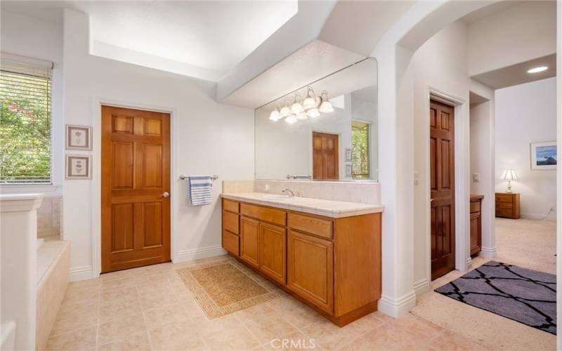 There is plenty of room to spread out and have your own space with the dual vanities and expansive countertops.  Notice the custom soffit lighting above.  The door leads to the private commode room.