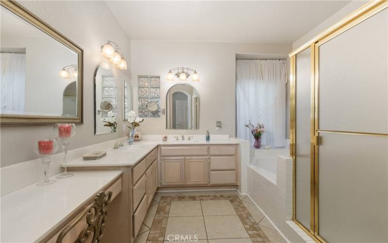 The main bathroom features double sinks, a full soaking tub, and a large shower enclosure. There is also a vanity place where you can sit comfortably and prepare for your day.