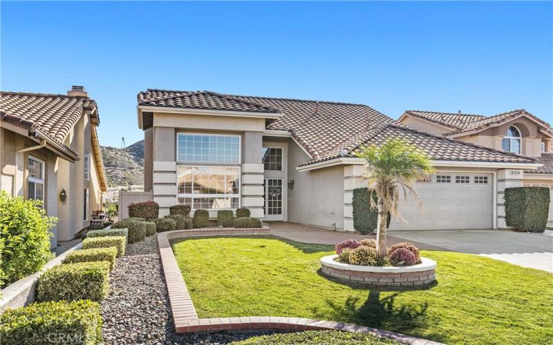 The front yard features mature landscape and hardscape design featuring an accent island for flowers and a brick walkway to the front door.