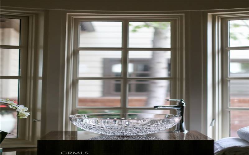 Antique crystal vessel sink reflects shimmering light from exterior gas lanterns.