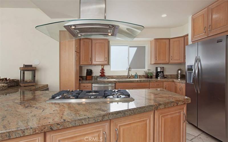The kitchen features granite counters, gas cooktop, vent hood and stainless steel appliances