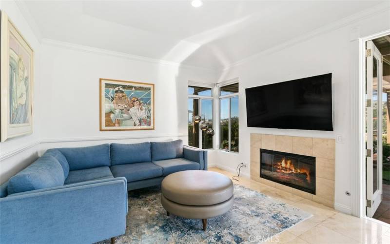 Family room with wall mounted TV and fireplace.