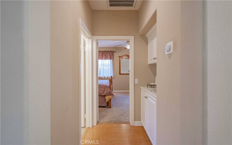 Hallway also has white custom built in cupboards that compliment the kitchen and bedrooms. White trim around the baseboards and doorways.