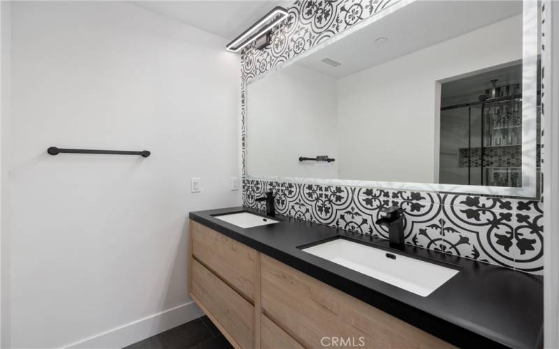 The primary bathroom has a modern double sink with black counter top, and a designer mirror with WiFi and back lighting.