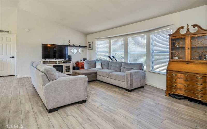 Open living area with vaulted ceilings and bow window.