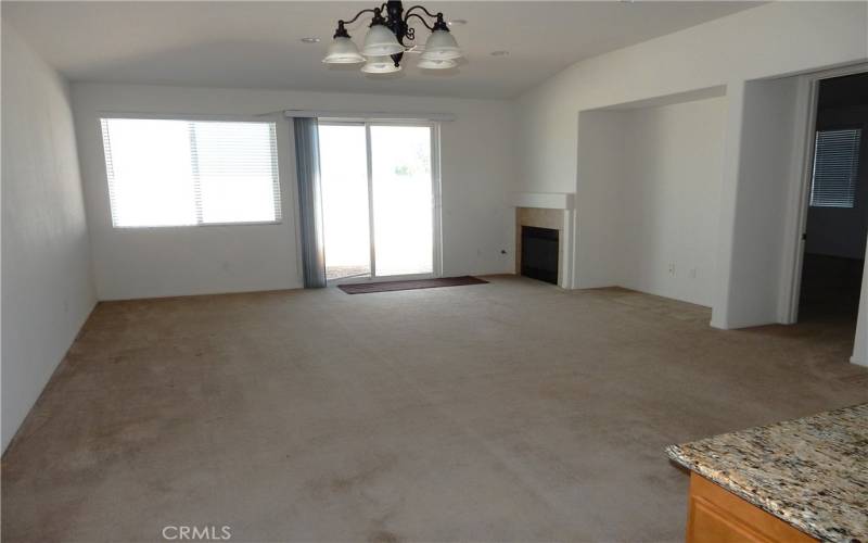 Open family room with a fireplace off of the kitchen and dining area.