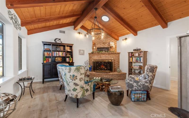 library with planked wood beam ceiling and brick fireplace
