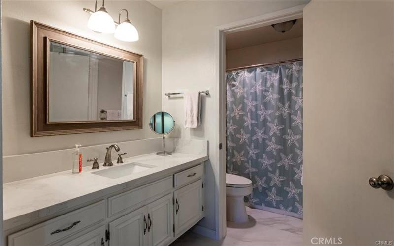 The bathroom features a quartz counter top, tile flooring and a privacy door to the shower over tub and toilet.