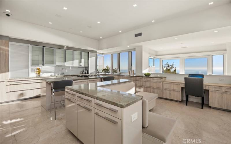 Gorgeous state of the art modern kitchen with stone counter and sleek cabinets with glass windows for enjoying the view while cooking