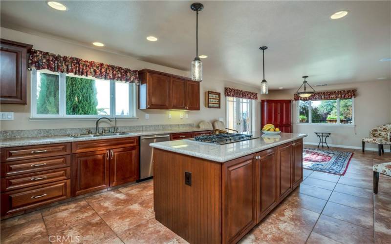 Graceful kitchen with Bosch cooktop in island and dining area with doors to covered tile deck.