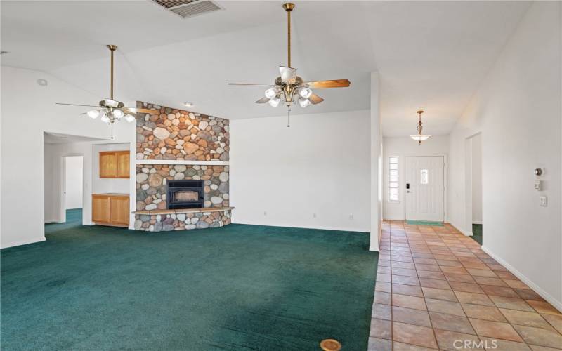 Family room with stone wood burning fireplace and vaulted ceilings open to kitchen.