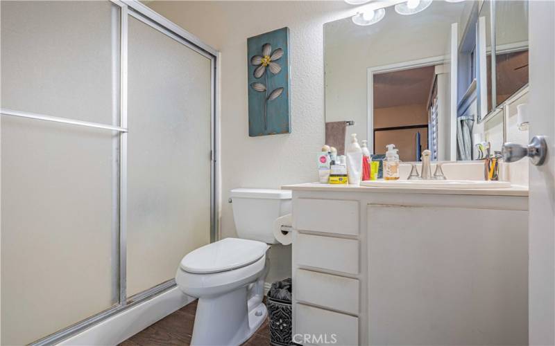 Primary en-suite bathroom features a walk-in shower, vanity sink, mirror, lights above and is tiled.
