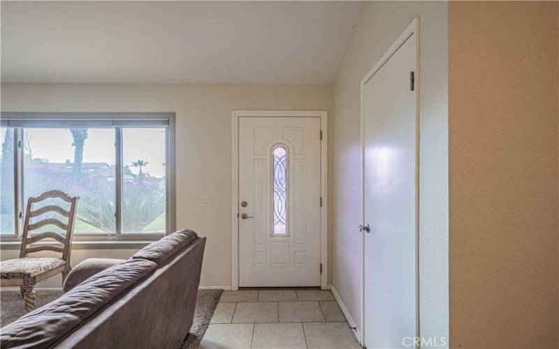 Front door has tile walkway, and a coat closet to the right of entrance.  The front window that overlooks your front yard.  Carpeted Family Room fireplace side. Tiled pathway leads to the kitchen side of the great room.