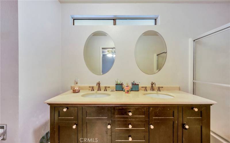 Primary bathroom with dual sinks and shower over tub.