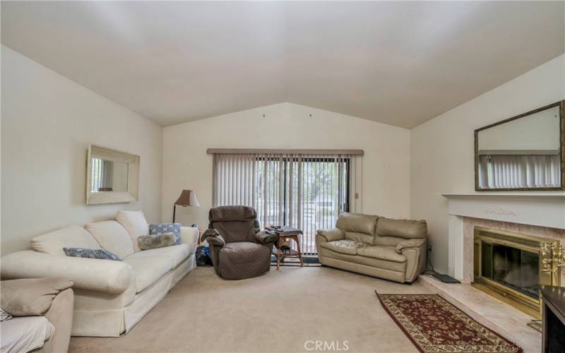 Large sunken living area has vaulted ceilings, a sliding door to front deck and a fireplace.