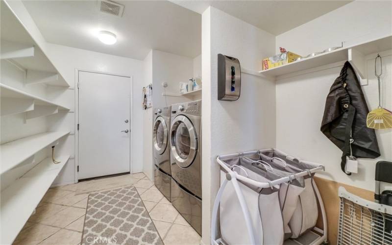 laundry area, located off the garage entry, has pantry shelves for added storage.