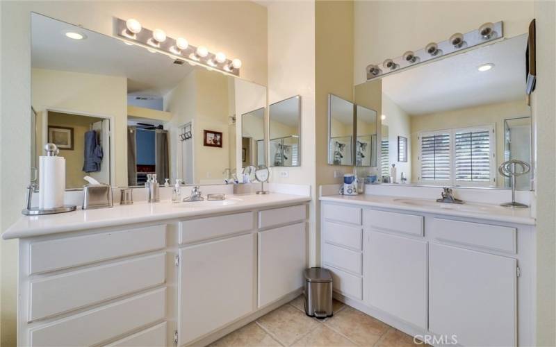 Primary bathroom with walk-in closet, bath tub, separate walk-in shower, double vanity area and sinks with storage underneath.