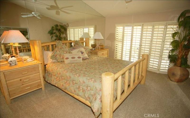 California King Bed in Master Bedroom with Plantation Shutters and TV