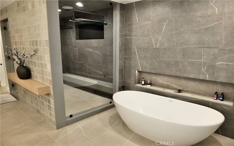 Bath tub with a faucet that comes from the ceiling into a wet room