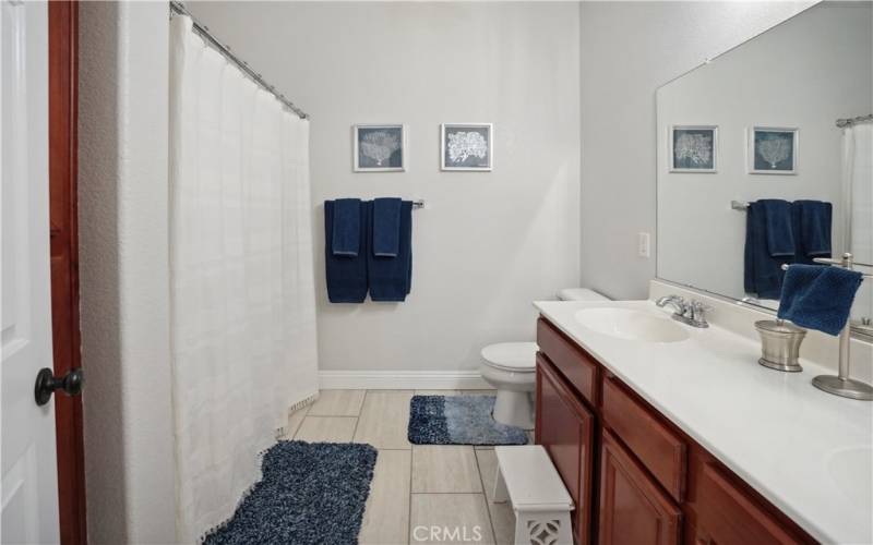 Hall Bathroom with dual sinks, tub/shower and large linen cabinets