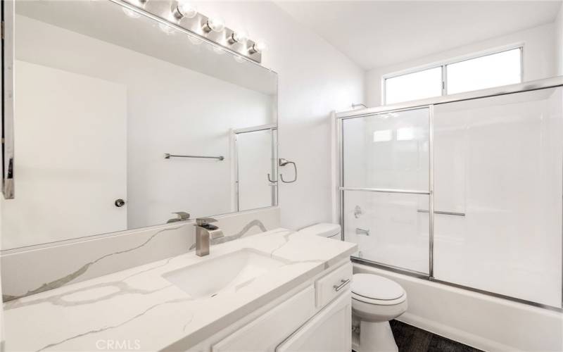 Full bathroom (upstairs) between 2 bedrooms - New faucet, quartz countertops, lighting, shower door, and flooring