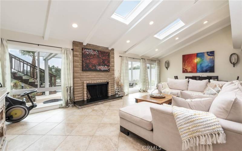 Spacious living room with beamed ceiling, skylights and fireplace. View both sunset and sunrise.