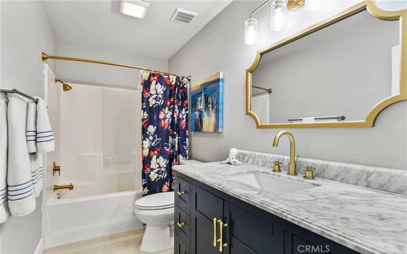 This bathroom has been upgraded with gold fixtures and stone countertop.