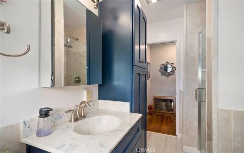 A fully renovated bathroom featuring extra cabinets to store linens.