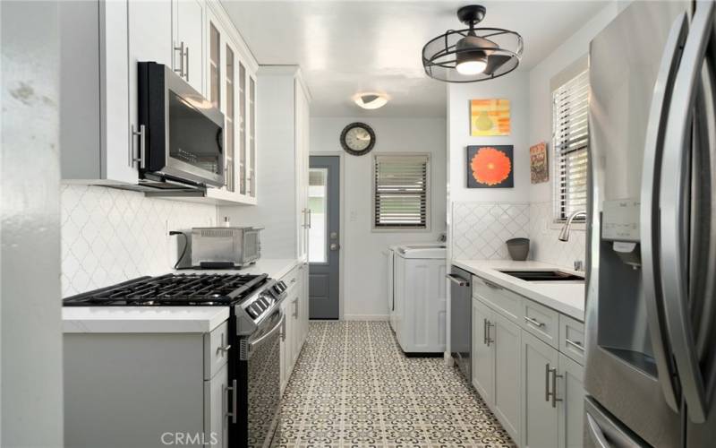 The kitchen has been upgraded with newer cabinets, quartz countertops, a custom backsplash, and stainless steel appliances, adding modern flair to the home.  An interior laundry room off the kitchen adds convenience to everyday chores.