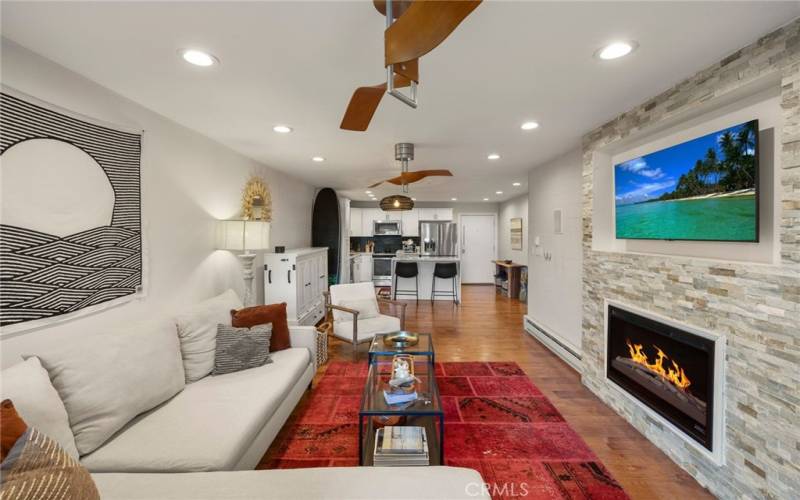 The living room features a fireplace, ceiling fans, and wood flooring.