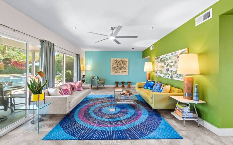 The colorful living room with wall of windows opening to the backyard.