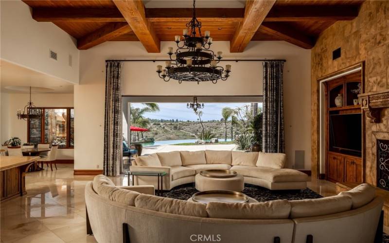Family Room with vaulted ceilings, large wood beams and triple layer rustic Spanish Chandalier