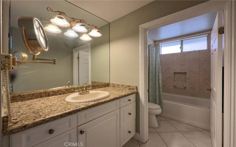 Master Bathroom remodeled with newer lighting, granite counters, and tiled walls in shower/tub area