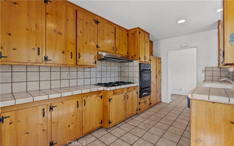 Kitchen with vintage knotty pine cabinets and tile counter tops.