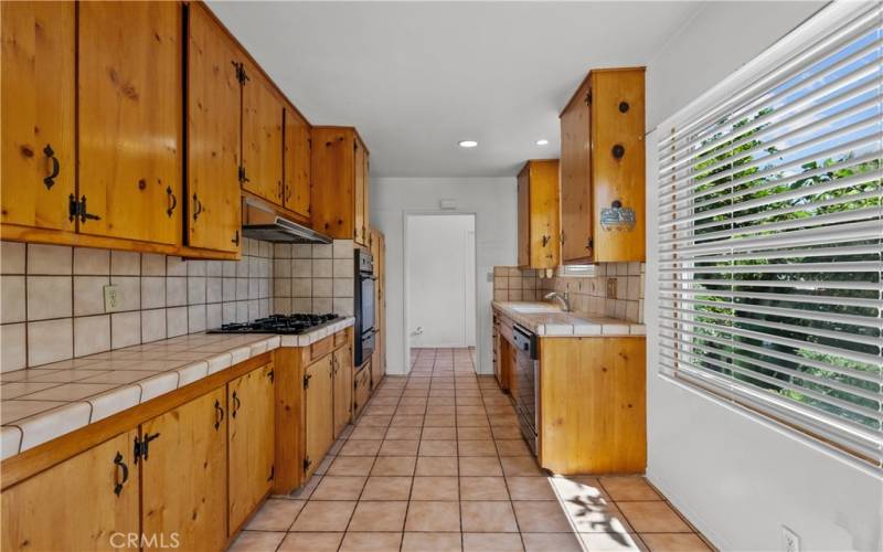 Kitchen with vintage knotty pine cabinets, tile counter tops and breakfast nook.