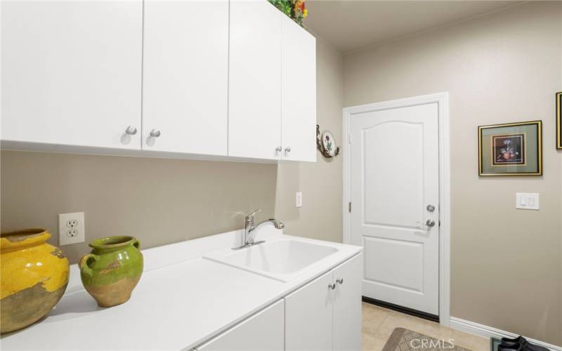 Laundry room includes a sink with counter and plenty of storage