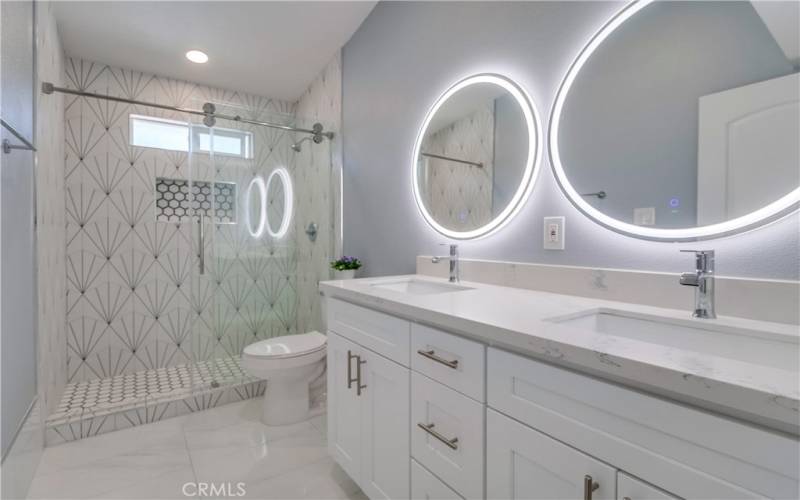 The front bath with gorgeous tile work in the walk-in shower, dual sinks, and lighted mirrors