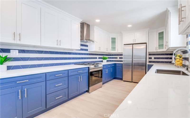 Wow! This kitchen is stunning with quartz countertops, custom tile backsplash, two-tone soft-close Shaker cabinetry, recessed lighting, and stainless steel appliances