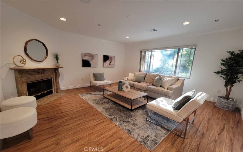 Living room with high ceiling, view of trees & greenery, fireplace, engineered floors.