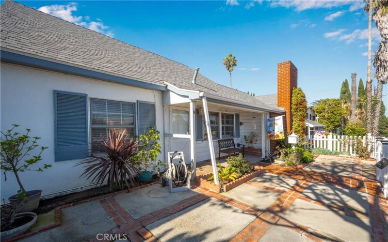 Front porch features charming enclosed garden with brick/cement walkway & patio
