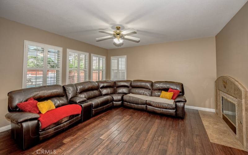 Warm fireplace, ceiling fan in the living room of this home just opposite of the kitchen, large space for those gathering or a cozy evening at home.