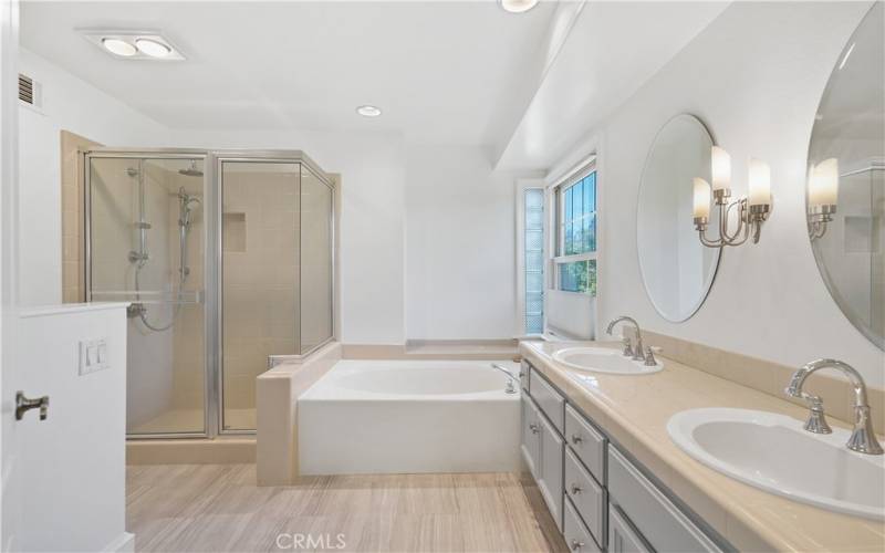 Attached primary bathroom with separate soaking tub and walk in shower with dual shower heads