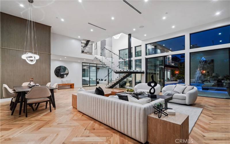  
Grand-Scale Great Room w/ a Wall-to-Wall Sliding Glass Doors overlooking Stunning Backyard & Floating Quartz Staircase w/ a Glass Panel Railings.