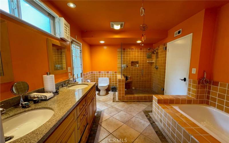 Primary bathroom with glass enclosed walk-in shower, bathtub and double sink.