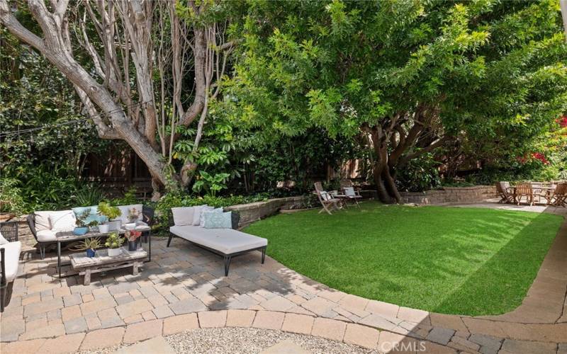 The rear yard is incredibly private, with multiple spaces for entertaining framed by manicured landscaping and mature shade trees.