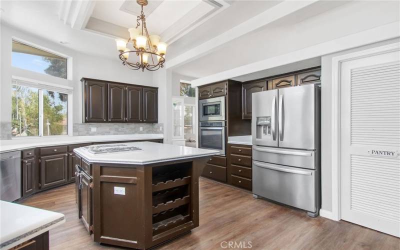 Large island with cooktop, walk-in pantry, built in wine rack, corian countertops