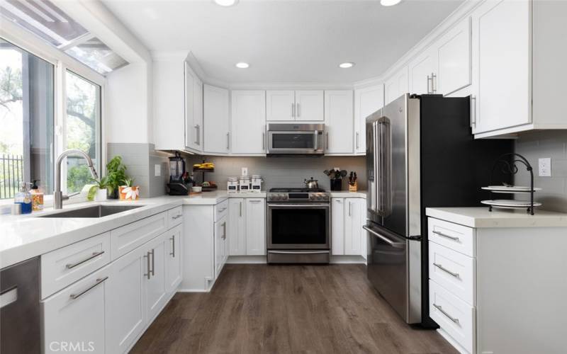 The kitchen features white mission-style soft-close cabinets and stainless steel appliances.