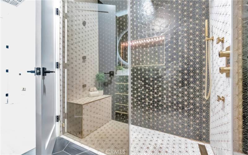 Spa-like shower with gold-trimmed tile and triple function rain, handheld shower heads and body sprays